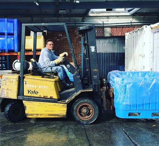 a forklift operator lifts a bin of seafood at a Red's Best facility