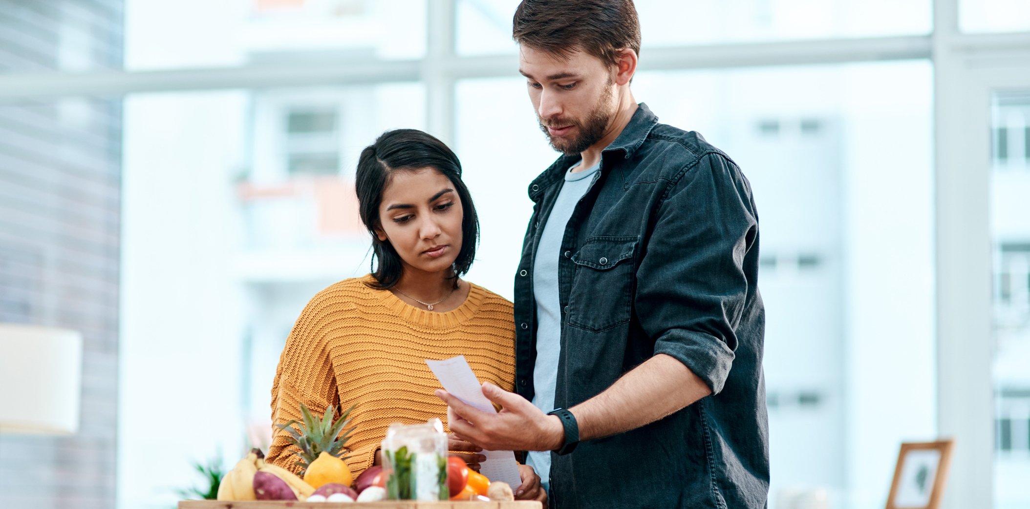 couple looking concernedly at grocery store receipt