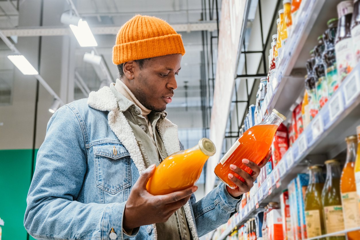 man-comparing-juices-in-supermarket