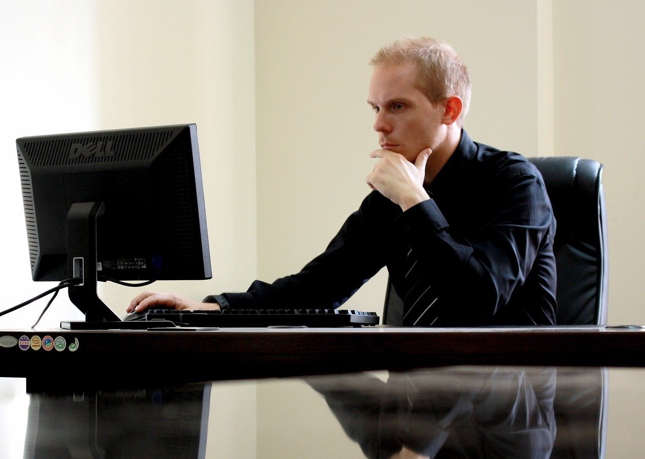 man in office at computer thinking and deciding