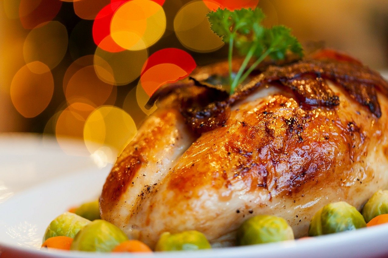 roasted turkey sitting on serving tray with brussels sprouts and carrots